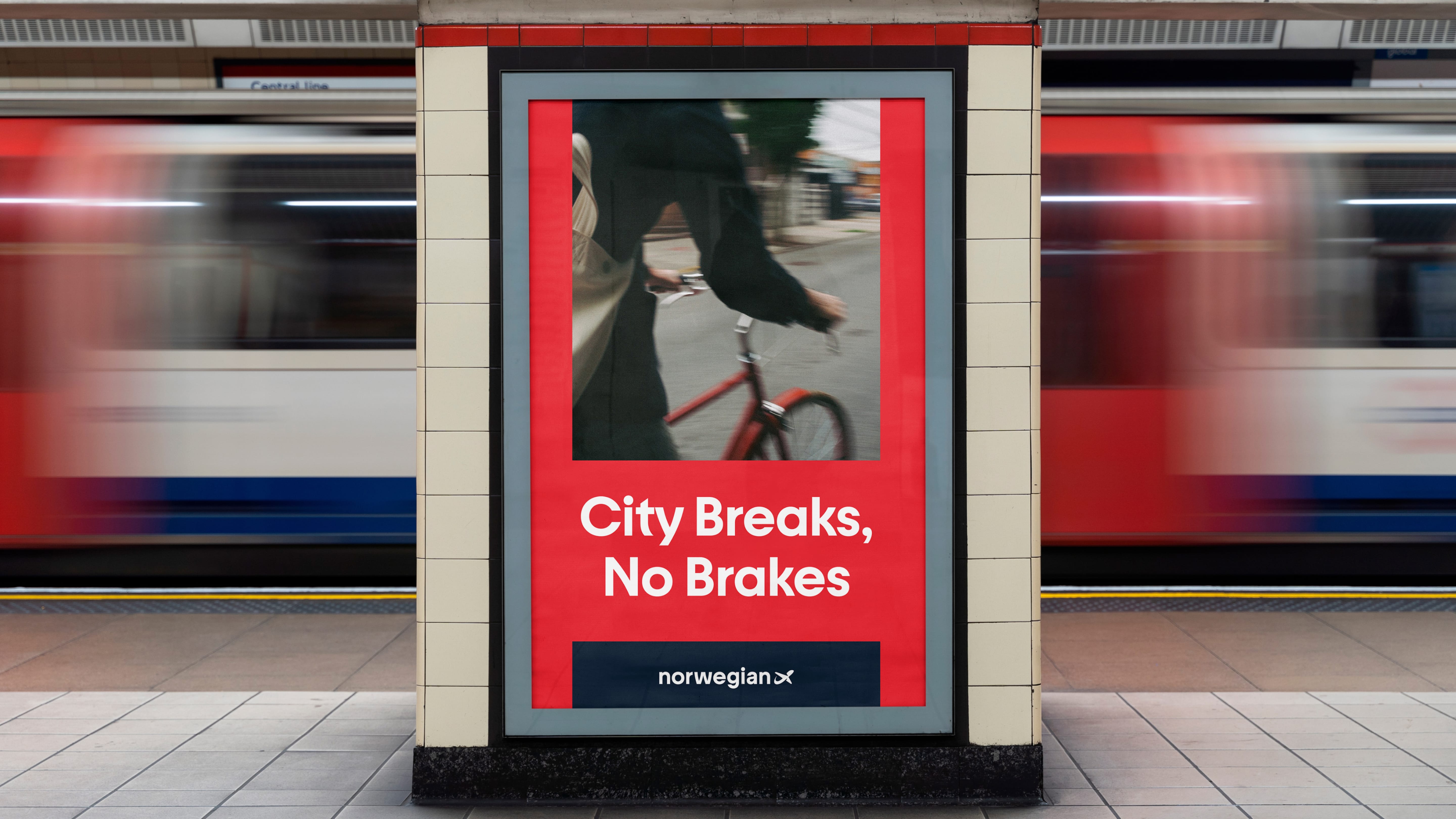 A red poster in a train station reading City Breaks, No Brakes, with a train blurring past behind it