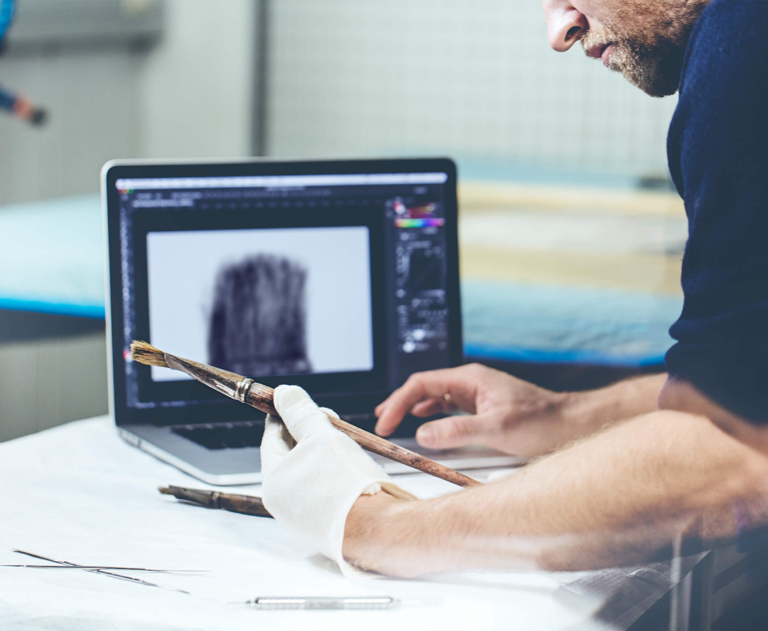 Conservator in gloves holding Edvard Munch's paintbrush up to a laptop screen while digitizing it