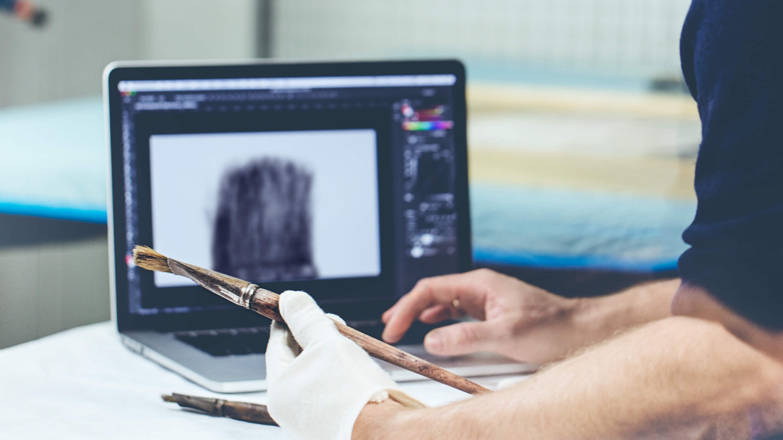 Conservator in gloves holding Edvard Munch's paintbrush up to a laptop screen while digitizing it