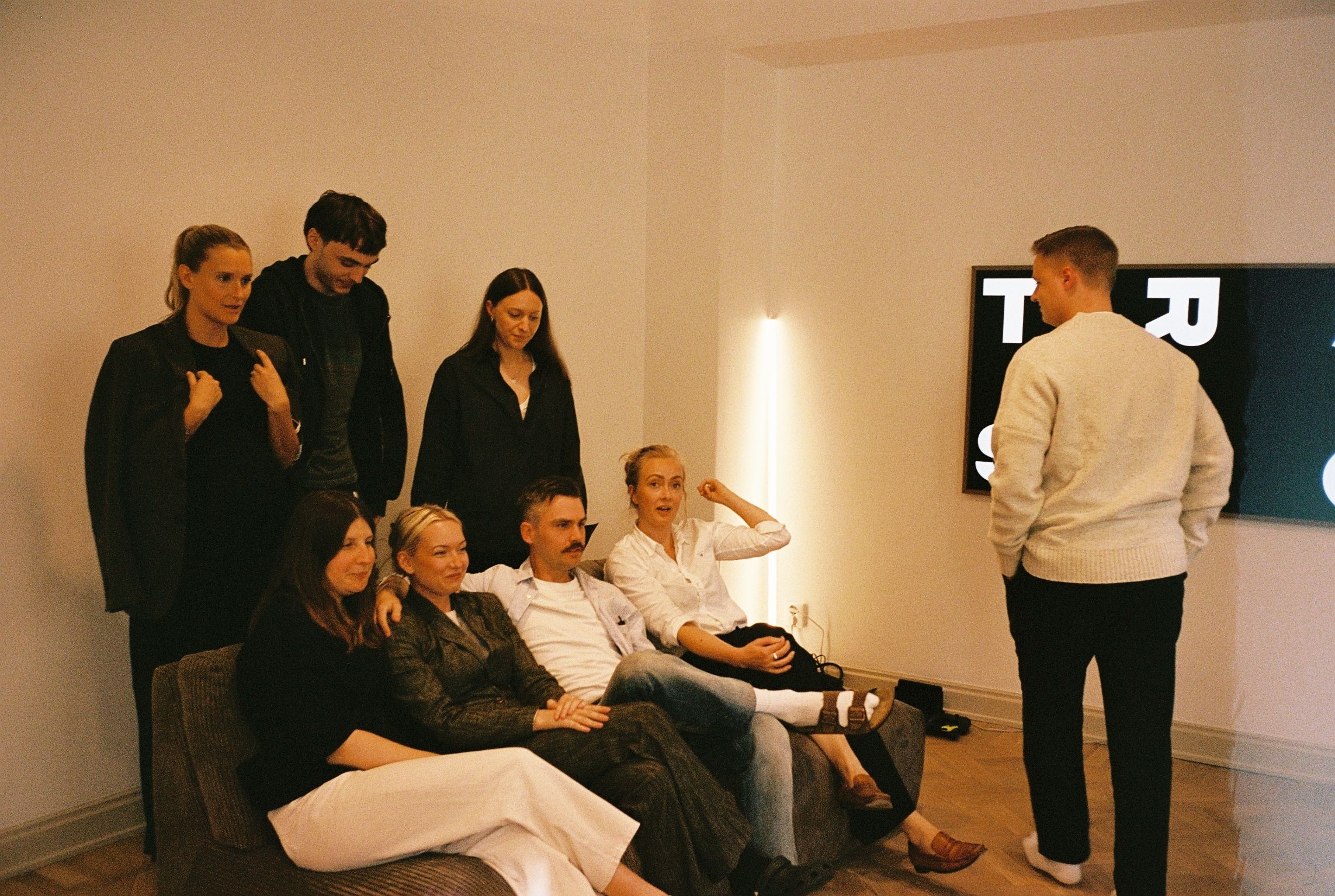 Colleagues gathered around a sofa in front of a screen