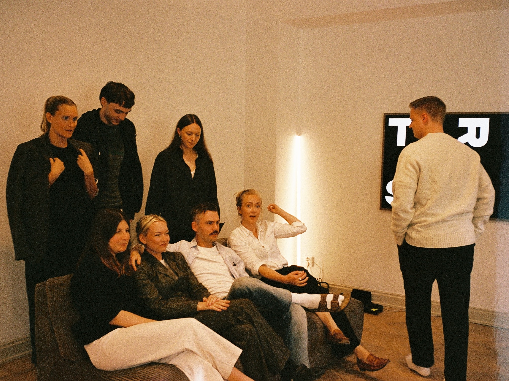 Colleagues gathered around a sofa in front of a screen
