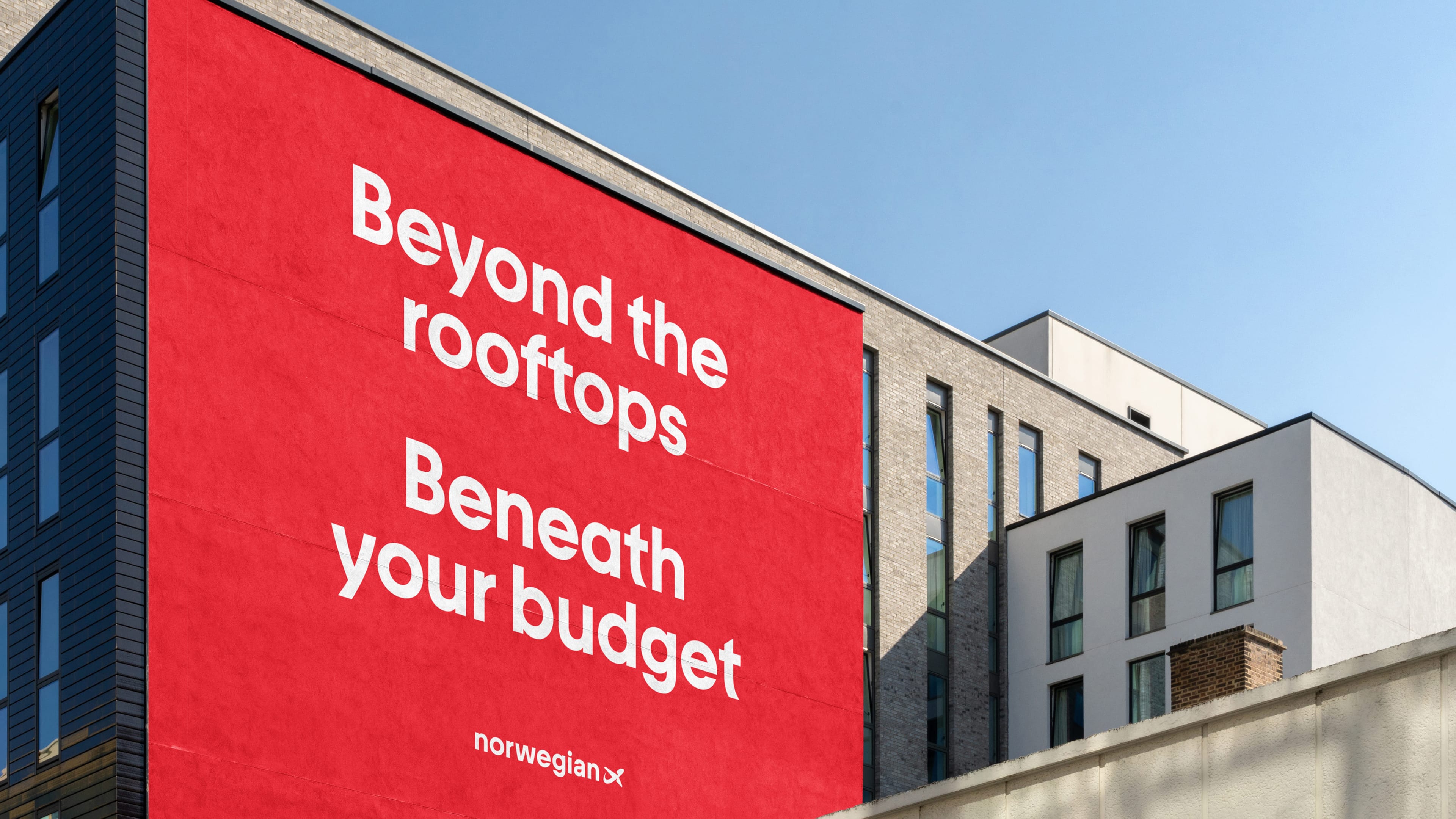 A red billboard on the side of a building reading Beyond the rooftops, Beneath your budget