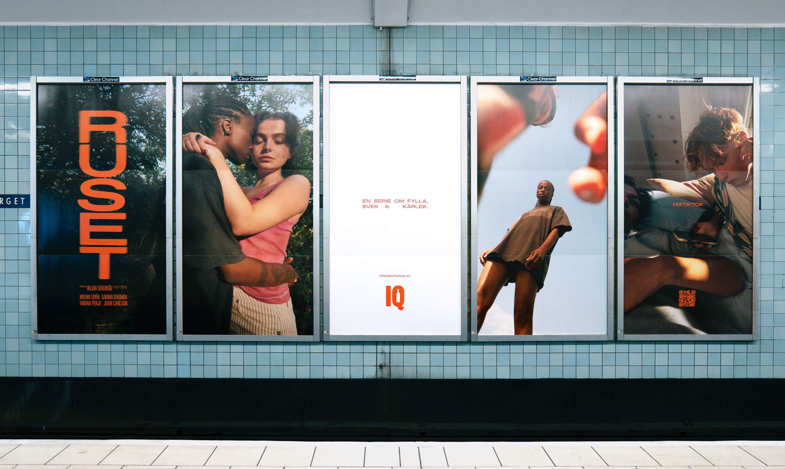 A cylindrical street advertising kiosk showing the RUSET title poster with the embrace image and cast credits, photographed at street level with a cyclist passing in soft focus.