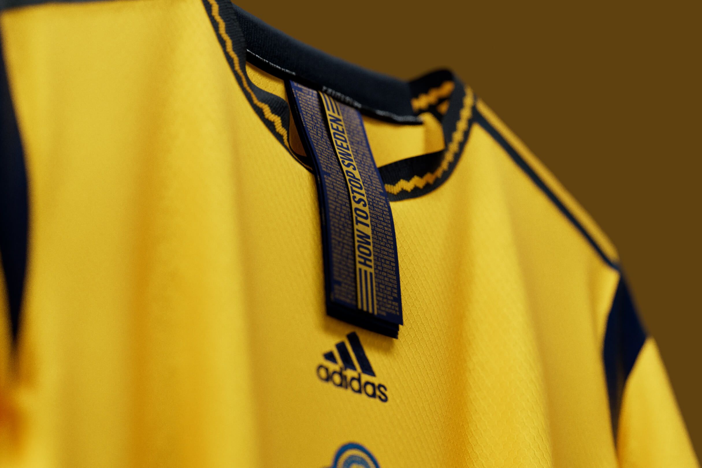 Close-up of a Sweden women's national team jersey collar tag printed "HOW TO STOP SWEDEN" in small guide-style text, with the adidas mark below.