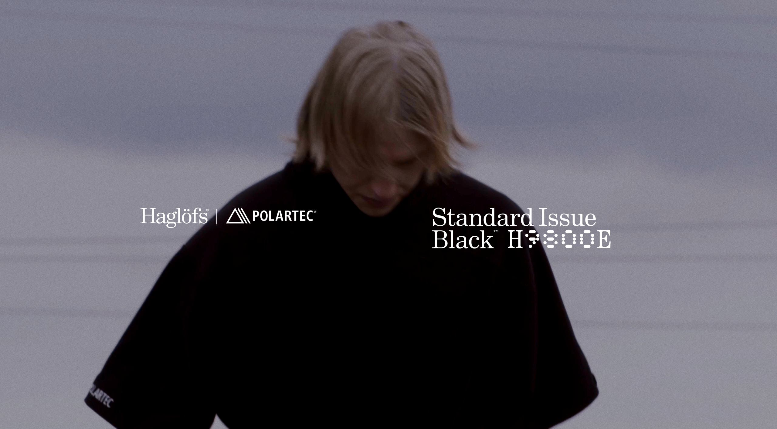 A person wearing a black t-shirt, with "Haglöfs POLARTEC®" and "Standard Issue Black