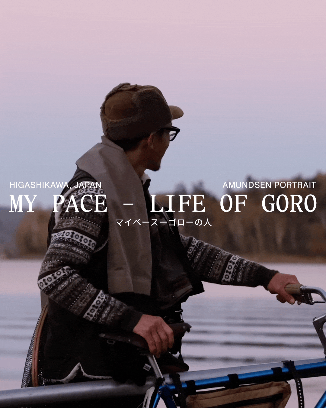 A man in a hat and patterned sweater holds a bicycle by a lake, looking into the distance, with the title "MY PACE - LIFE OF GORO."