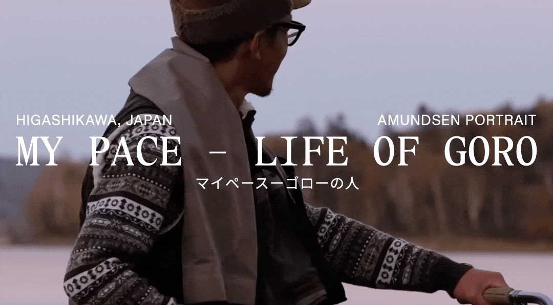 A man in a hat and patterned sweater holds a bicycle by a lake, looking into the distance, with the title "MY PACE - LIFE OF GORO."