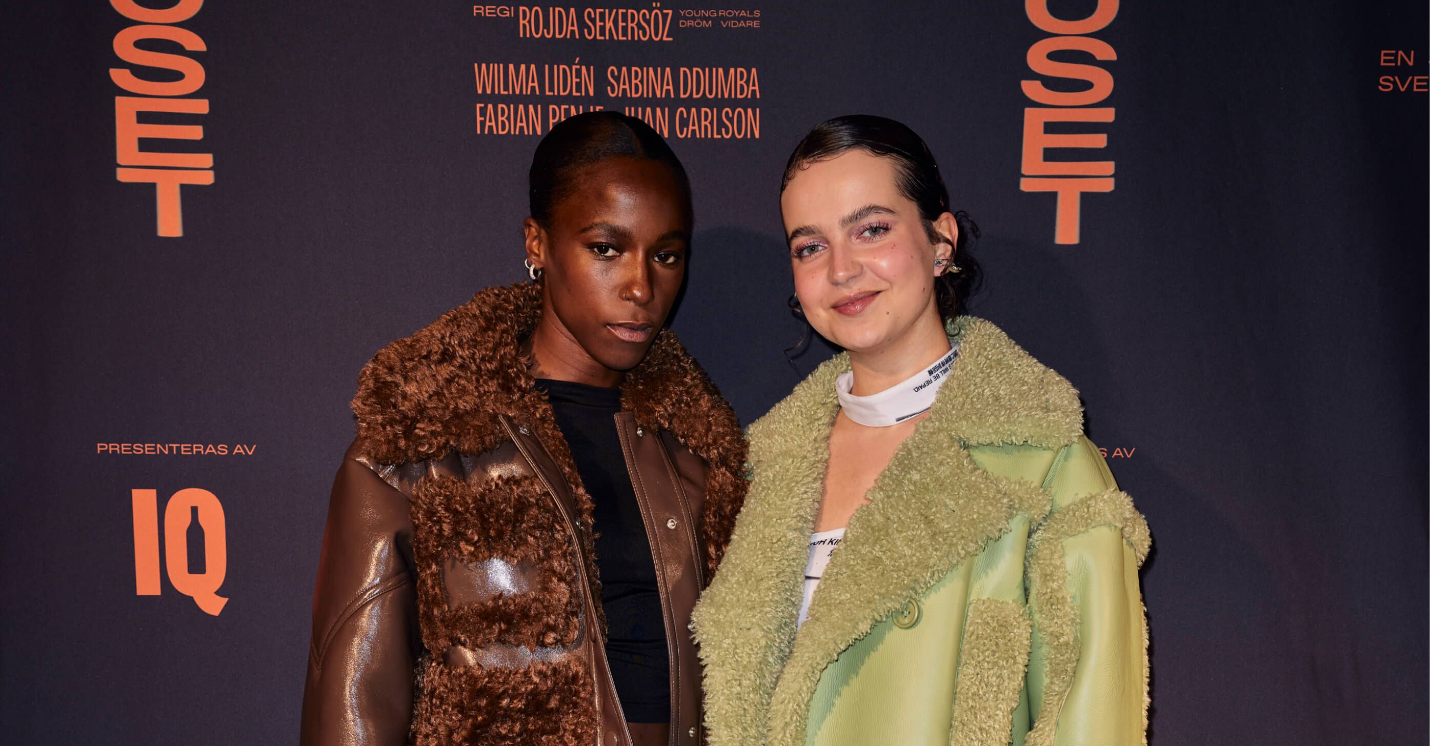 A red-carpet-style portrait of two young actresses posed together in front of the Ruset step-and-repeat backdrop at the premiere.
