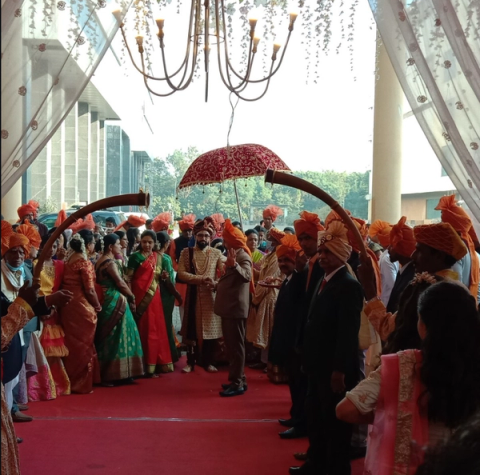 Groom arriving under a decorated umbrella with the procession