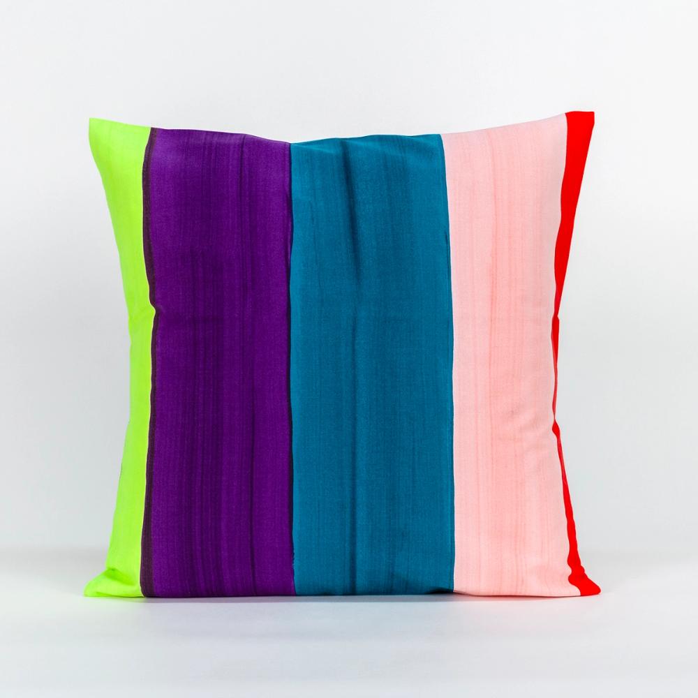 A square pillow featuring painted vertical stripes of purple, teal, chartreuse, light pink, and red.