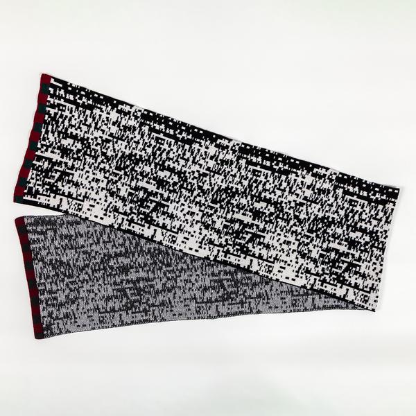 A long scarf with a pixelated black and white pattern, folded in a V-shape. The left edges of the scarf include a maroon-colored border.