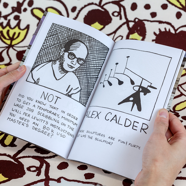 A photograph of a book standing upright against fabric yardage consisting of brown and yellow floral motifs. Each page of the book is dedicated to a famous male artist. On the left, a portrait of an artist offers a ruling on whether they are hot or not. On the right, we are introduced to another artist, Alexander Calder, with a cartoon version of their work.