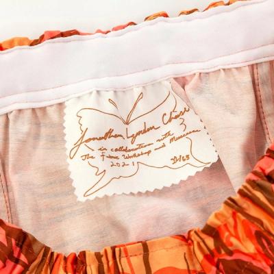 A detail shot of the inside of the shorts, showing the hand-screenprinted tag. The tag reads as follows: "Jonathan Lyndon Chase in collaboration with The Fabric Workshop and Museum 2021" the text is framed by a line drawn butterfly silhouette, and the bottom right corner notes the edition number "22/65"