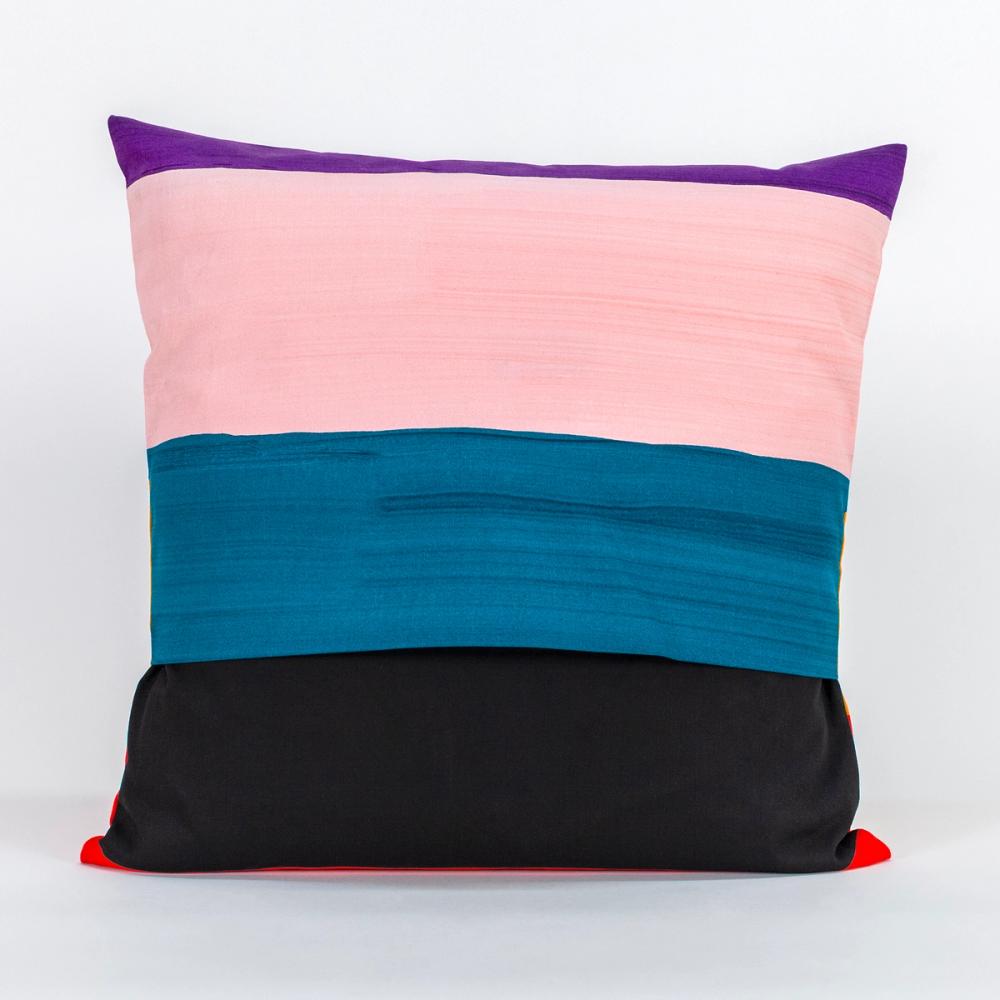 A square pillow featuring painted horizontal stripes of purple, light pink, teal, black, and red.