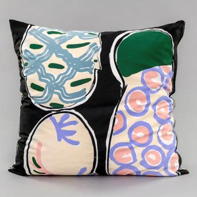 An image of a square pillow against a grey background. The pillow is a screenprinted design by Betty Woodman. The background of the design is black, with colorful pastel, loosely drawn, soft abstract shapes mimicking ceramic platters.