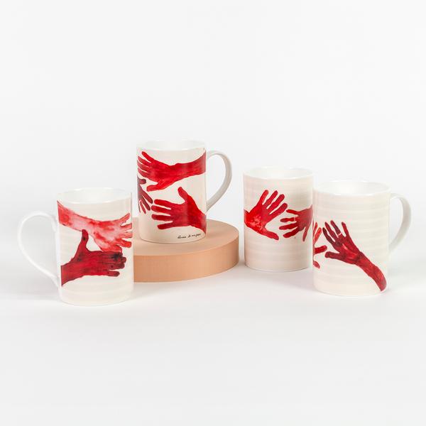 An arrangement of four tall cream-colored mugs with handles. Each mug features a different composition of red painted hands with fingers outstretched.