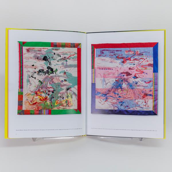 A photograph of an open book showing two images of abstract quilts, one on each page. The quilts have colorful borders made of solid and patterned fabric. The interior of the quilt is abstract with colorful and gestural lines and illustrations.