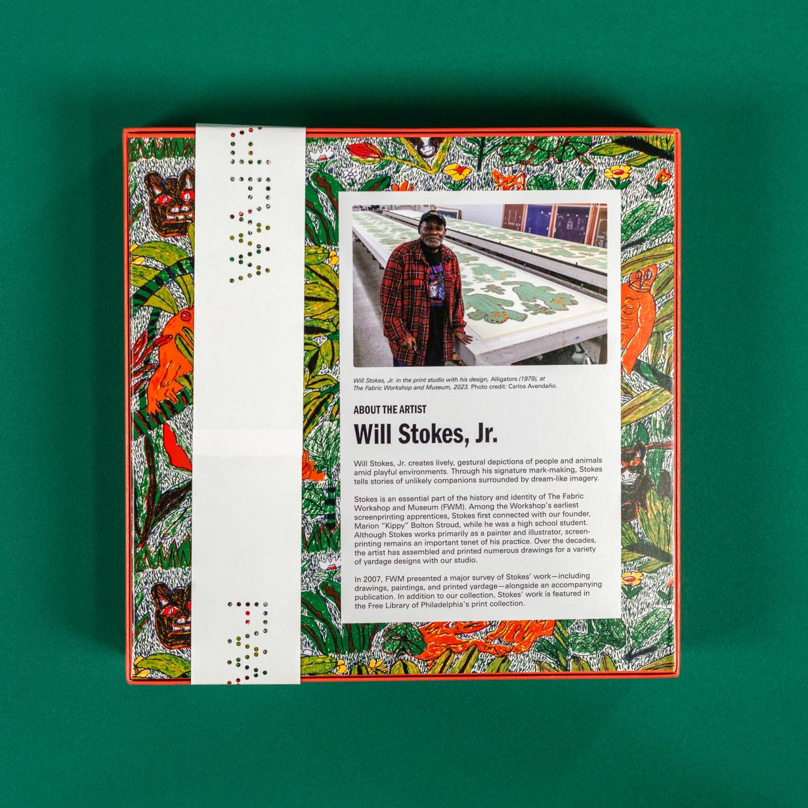 The puzzle is sitting against a dark green background face down and showing the back of the box. The back of the box has the same pattern as the front, but a white box includes a photo of the artist, Will Stokes, Jr., and a brief description of his work.