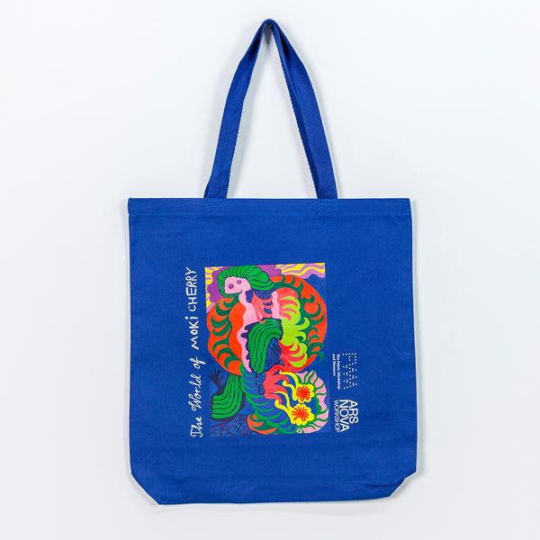 A blue canvas tote that features a colorful abstract painting composed of organic shapes. It reads "The World of Moki Cherry" and features the logos of The Fabric Workshop and Museum and Ars Nova Workshop.