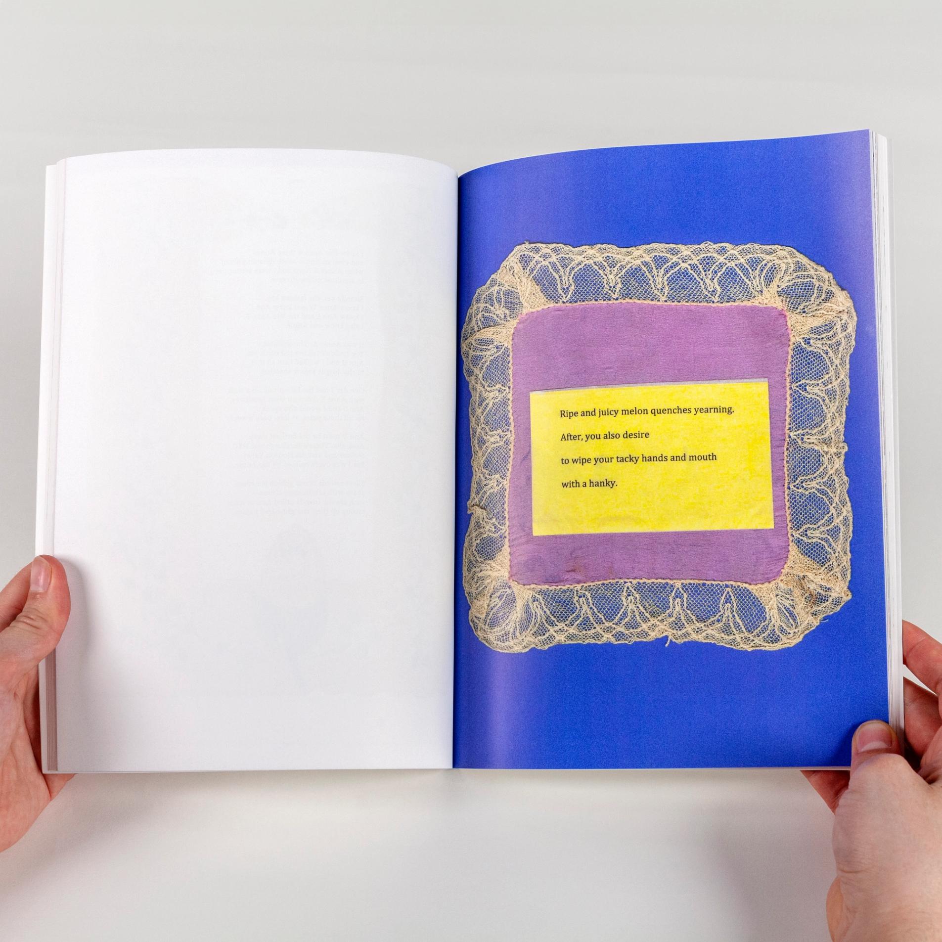 A photo of a person holding a book open. The left side of the page is blank white and the right side of the page has a royal blue background. There is a purple handkerchief with a cream, laced border. In the center there is a typed poem.