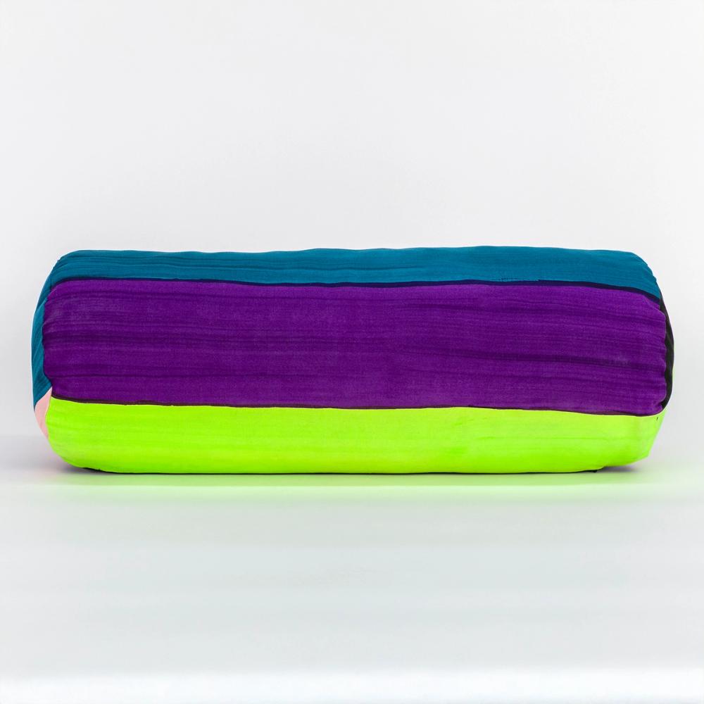 A wide round bolster pillow featuring painted horizontal stripes of, chartreuse, black, teal, light pink, purple, and red.