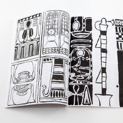An image of a book spread laying flat on a white surface. The spread contains four illustrations on the left page and one full-page illustration on the right. The illustrations are gestural and created with black ink on white paper. The drawings are of geometric and organic illustrations.