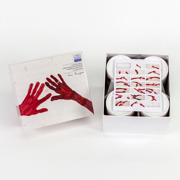 An open box next to its lid. The lid features a painting of two red hands with fingers outstretched. The hand on the right has a ring on its ring finger. The open box contains four white mugs with a postcard overlaid atop of them that shows a grid of 21 rectangles, 19 of which feature assorted compositions of red hands gesturing.