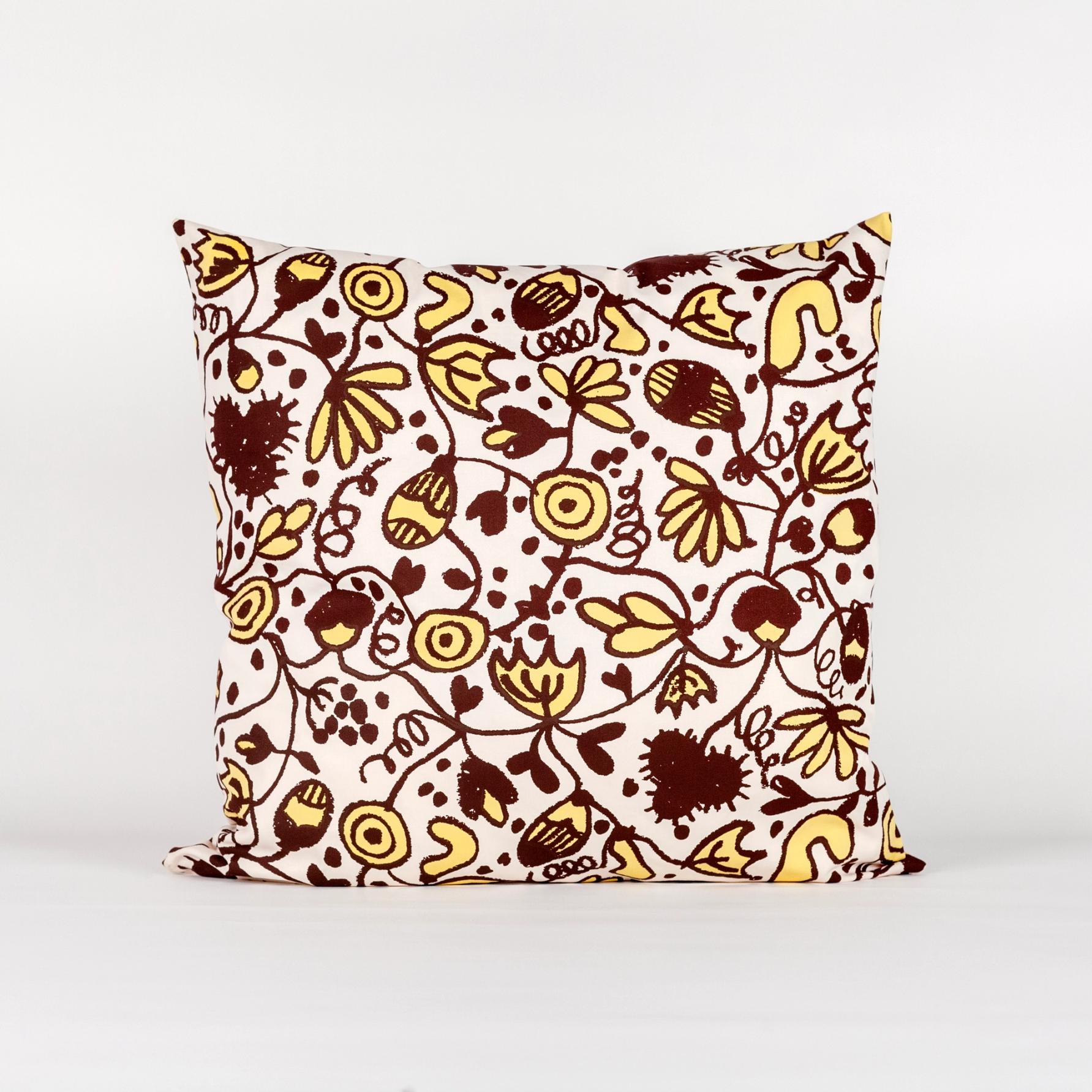 A square pillow made of fabric yardage consisting of brown and yellow floral motifs.