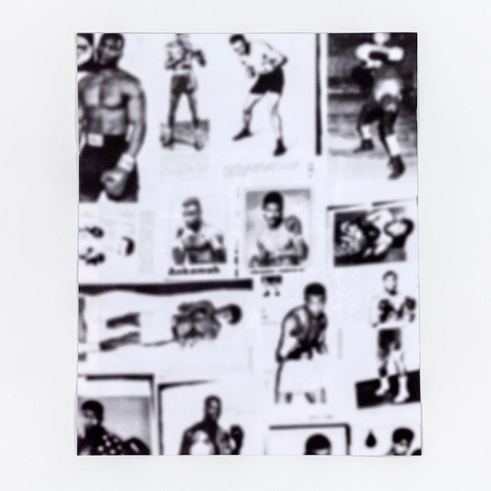 A photograph of the back of a large paperback book. The black and white back book cover features out-of-focus photos of many boxers in various poses.