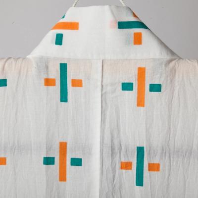 Close up image of the back collar of a white yukata with cross designs adorning the garment in orange and green.