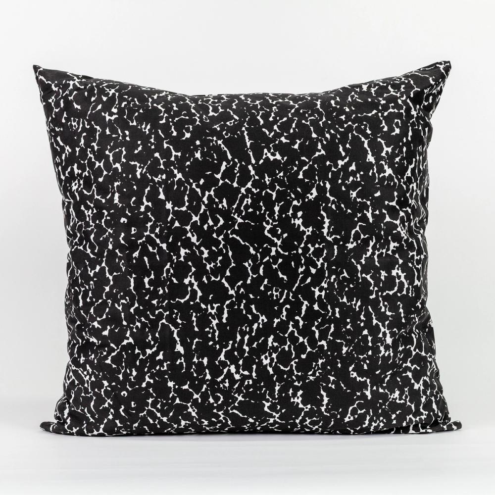 A square pillow featuring a speckled black and white design like the kind found on a student's composition notebook.