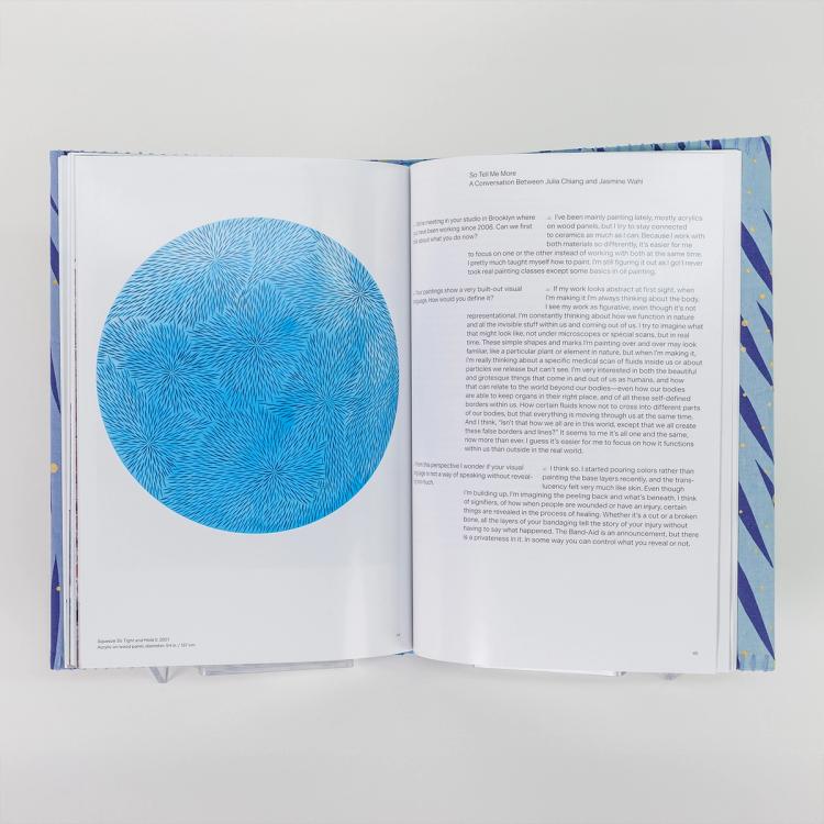 An open book featuring a large circular blue abstract painting made up of radiating line clusters on the left page, with printed text on the right.