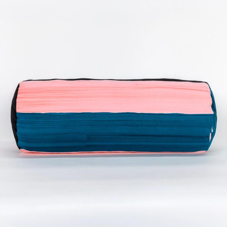 A wide round bolster pillow featuring painted horizontal stripes of black, teal, and light pink.