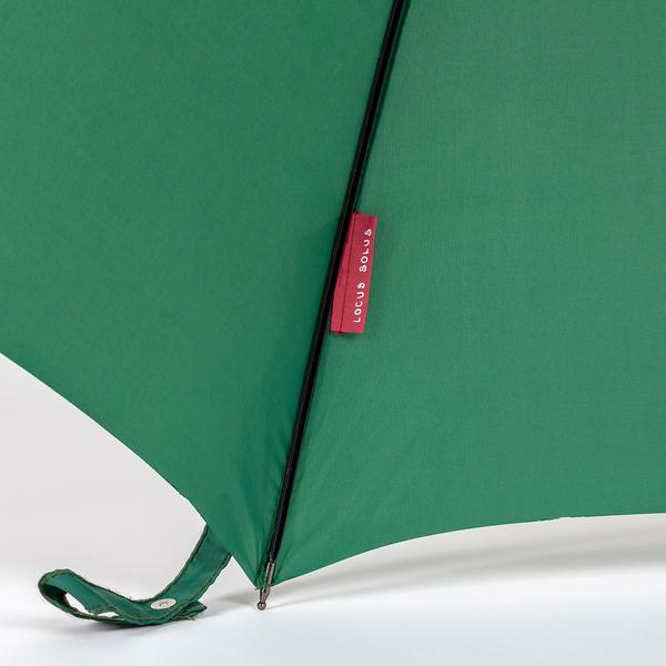 A detail of a green umbrella with a small red tag reading "Locus Solus"