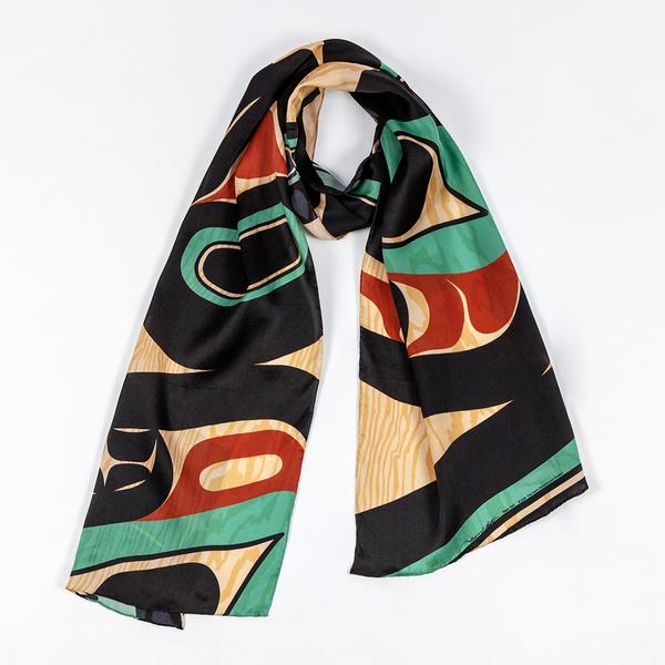 The scarf is draped in a circle, lying flat on a white backdrop. The scarf has a texture mimicking woodgrain, and has a striking pattern in shades of tan, red, turquoise, and black.