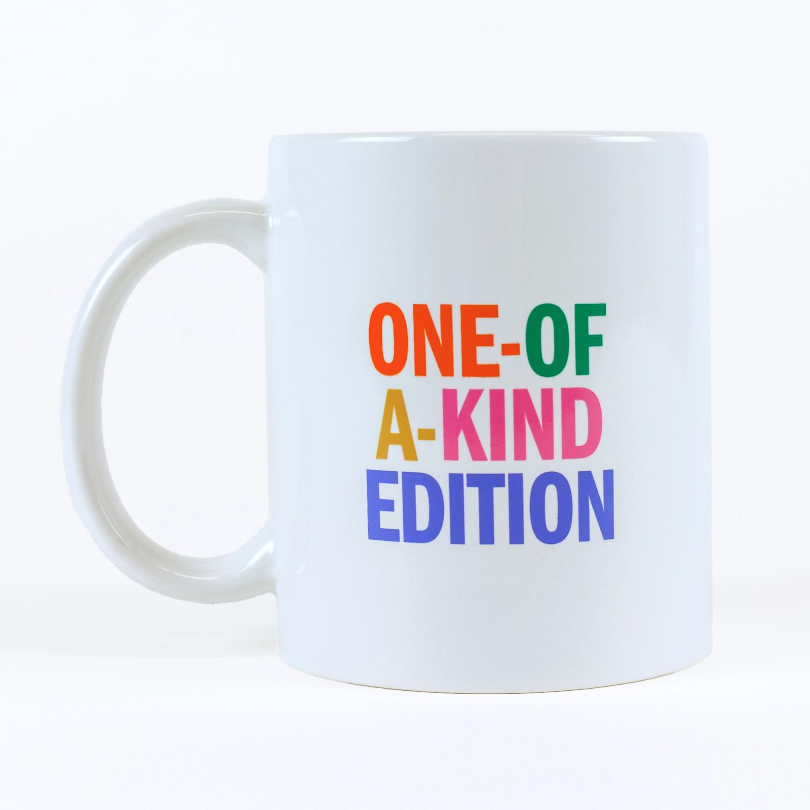 A cream colored mug against a white background that reads "ONE-OF-A-KIND EDITION". Each word is in a different color: orange, green, gold, pink and blue.