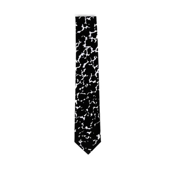 A folded tie featuring a speckled black and white design. The tie is mostly black as the irregular black blob-like shapes leave spare room for the white edges. 