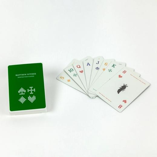 A hand of eight playing cards sits fanned out on a white backdrop, facing up. On the left, the box they are packaged in is displayed—it is a bright evergreen color with stylized renditions of diamonds, spades, hearts, and clubs in white. At the top, the box is labelled "Matthew Ritchie Proposition Player"