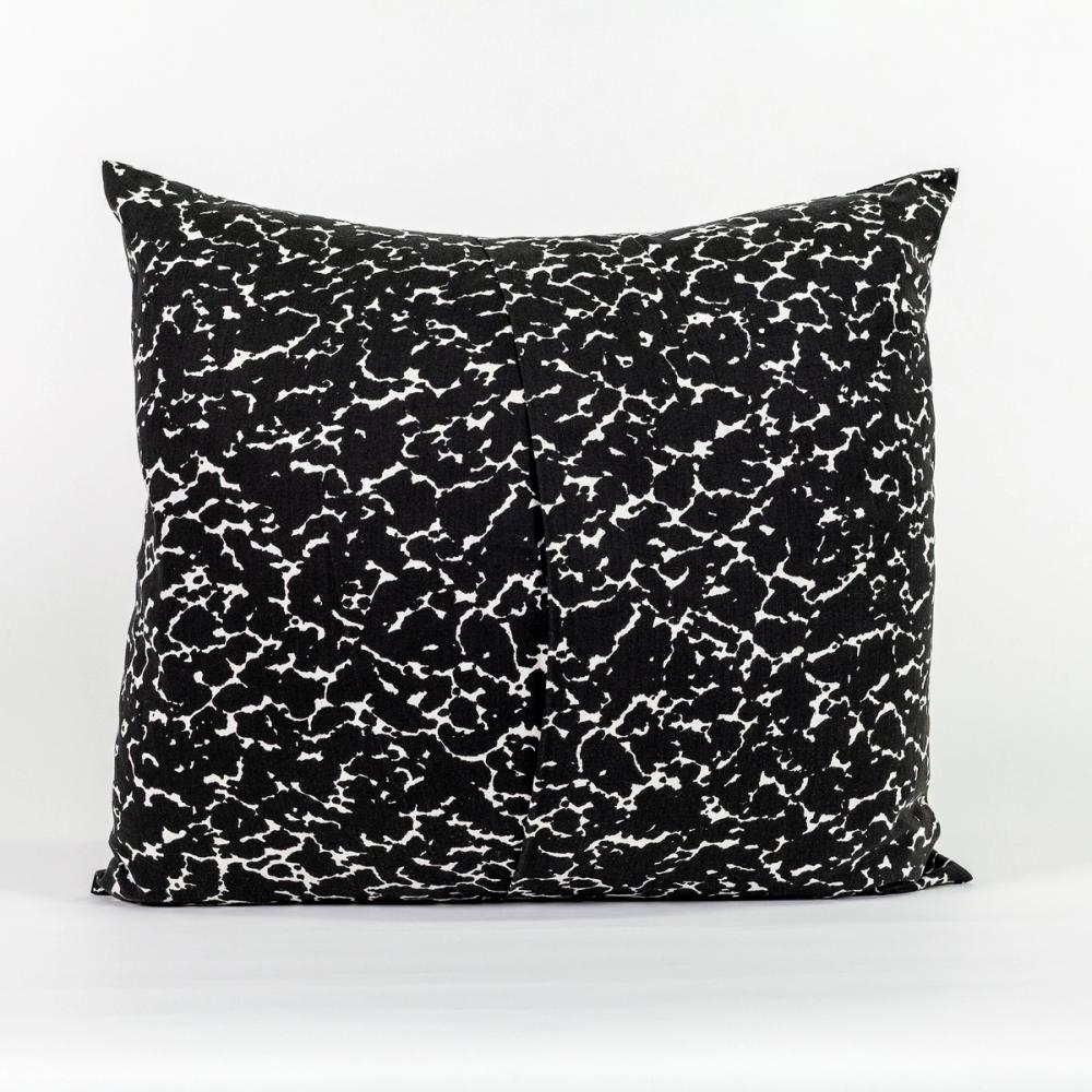 A square pillow featuring a speckled black and white design like the kind found on a student's composition notebook. The left and right panels of fabric overlap in the center to create an opening.