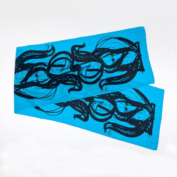 A silk scarf is folded and split diagonally against a white ground. This one is light blue and features bold, painterly gestures with ink drips and splatters that follow the curving motion of a brush.