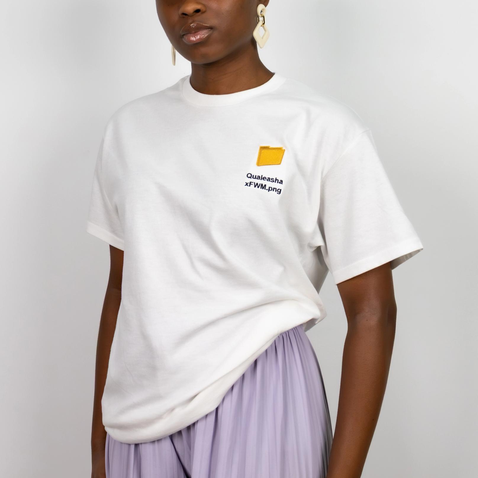 A photo of a model wearing a white t-shirt with a 1.5 inch yellow computer desktop folder embroidered on the upper left side of the shirt. Below the folder reads "Qualeasha x FWM.png" in black embroidery thread.