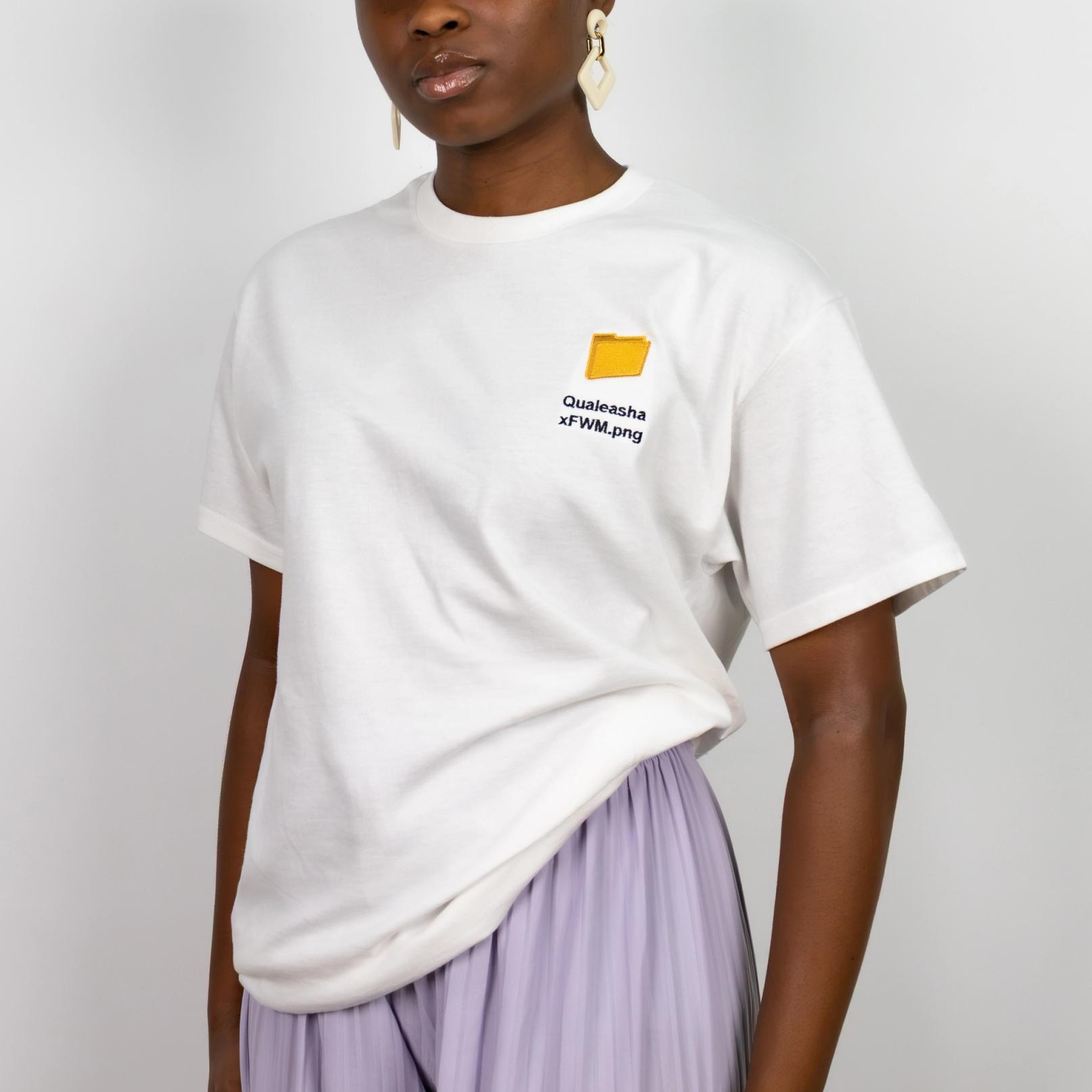 A photo of a model wearing a white t-shirt with a 1.5 inch yellow computer desktop folder embroidered on the upper left side of the shirt. Below the folder reads "Qualeasha x FWM.png" in black embroidery thread.