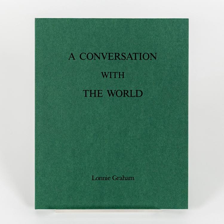 A photograph of a matte green hard cover book titled A Conversation with the World by Lonnie Graham