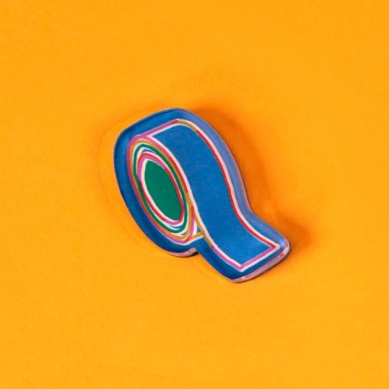 A tool magnet in the form of a colorfully outlined roll of blue tape is laid out against a bright, warm yellow background.