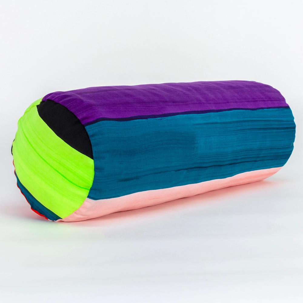 A wide round bolster pillow featuring painted horizontal stripes of, chartreuse, black, teal, light pink, purple, and red.