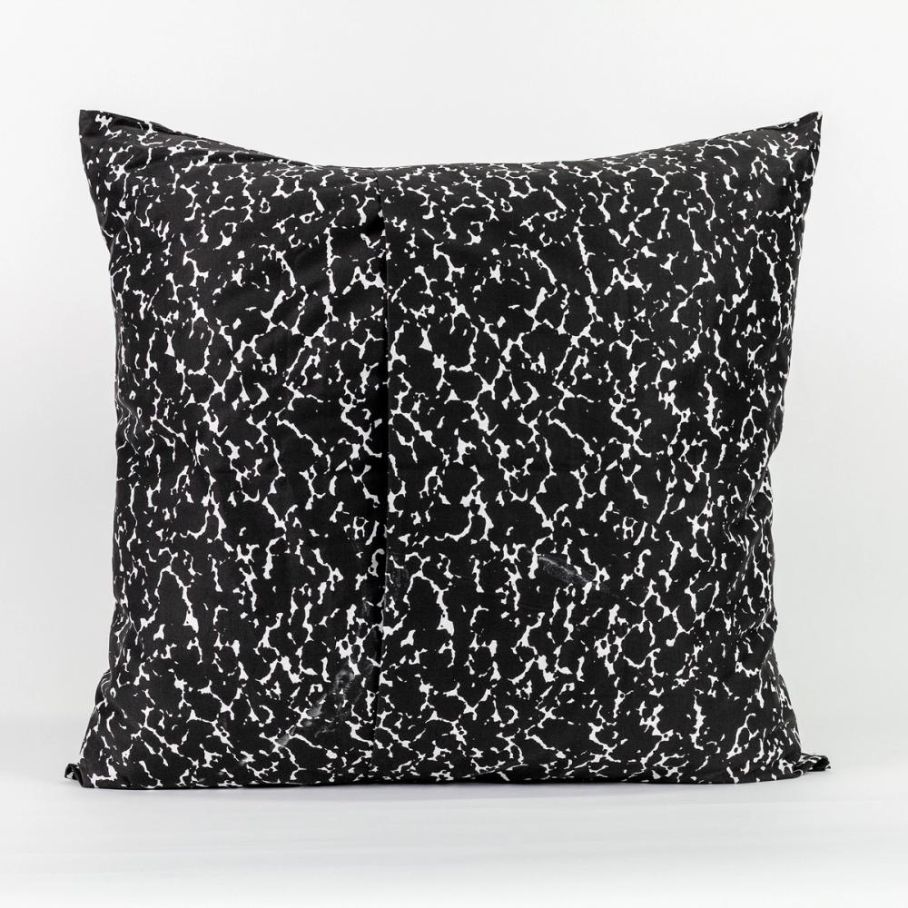 A square pillow featuring a speckled black and white design like the kind found on a student's composition notebook. The left and right panels of fabric overlap in the center to create an opening.