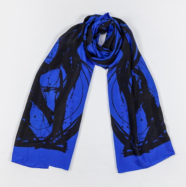 A silk scarf tied in a loose knot and laid against a white ground. This one is dark blue and features bold, painterly gestures with ink drips and splatters that follow the curving motion of a brush.