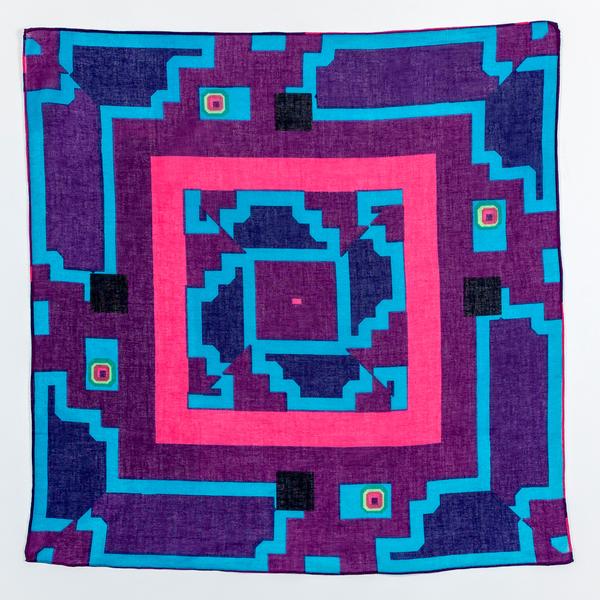One of the kerchief colorways sits flat against a white background. The scarf is purple, with varying shades of blue and a bright pink border around the designs in the center.