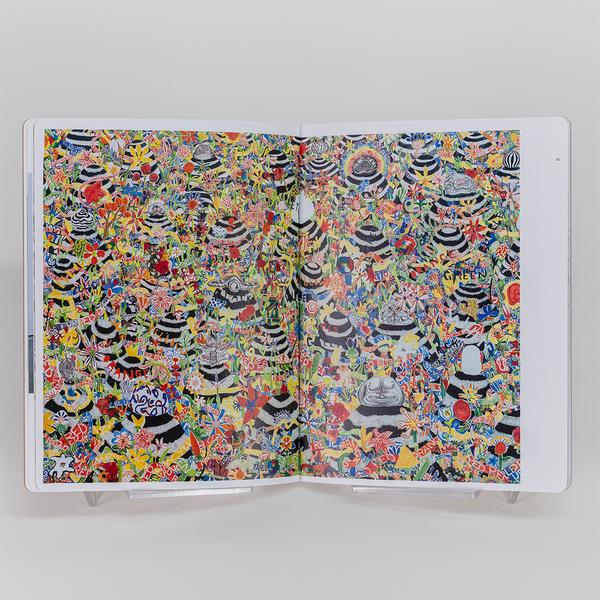 An open book showing a vibrant, densely layered artwork filled with colorful flowers, patterns, and text fragments, interspersed with black-and-white striped dome-like shapes.