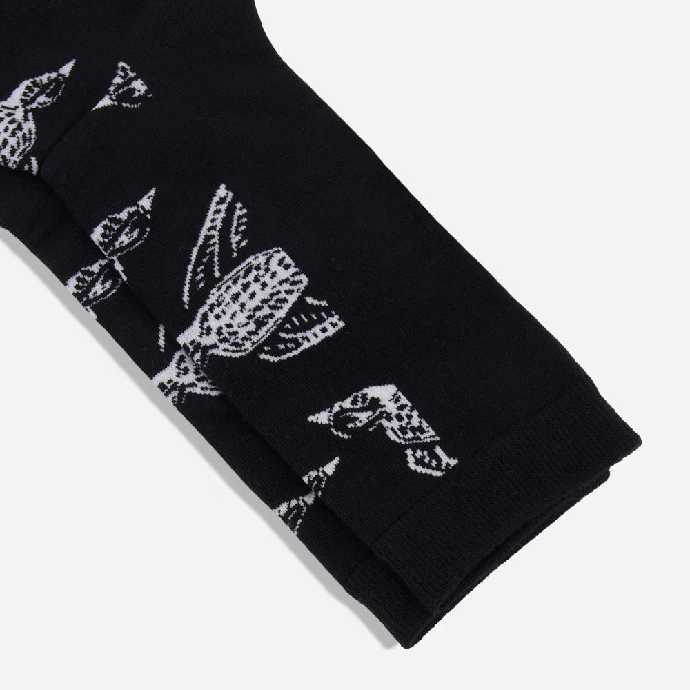 A detail of pair of black knit dress socks with a pattern of white illustrated Shomoro birds flying in different directions.